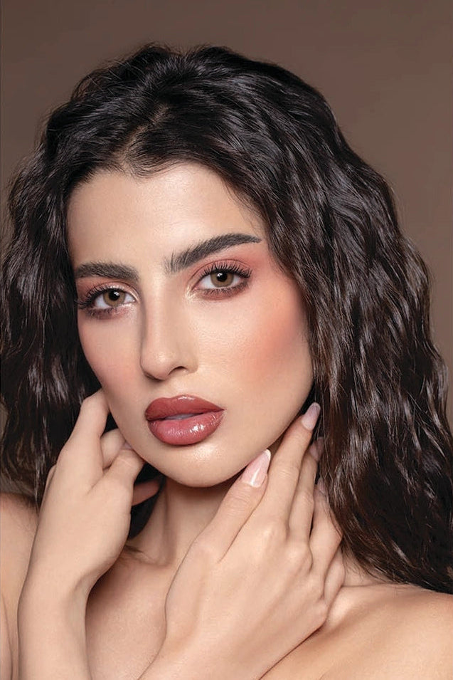 Woman with wavy hair and makeup on a plain background