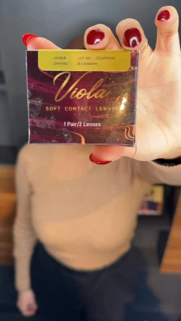 Hand holding a box of Viola soft contact lenses with a blurred background