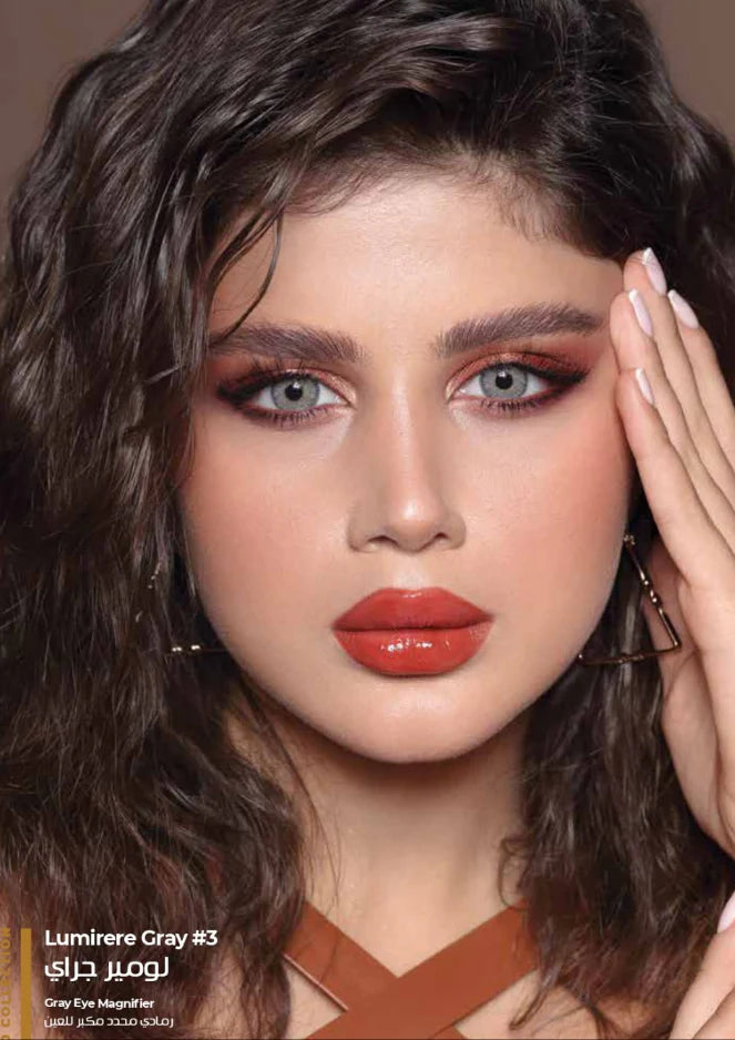 Close-up of a person with styled hair and makeup, wearing a brown top.